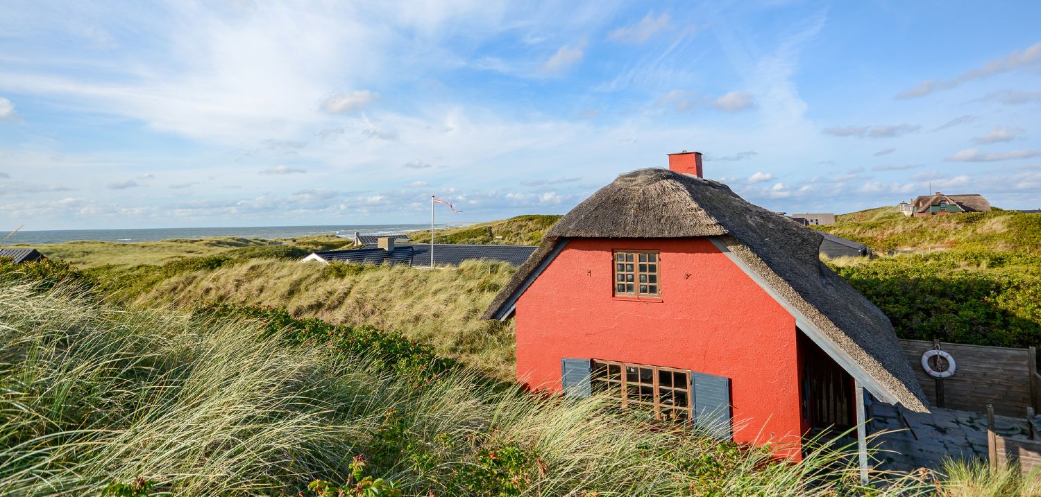 Rødmalet hus med stråtag ved Skagens kyst