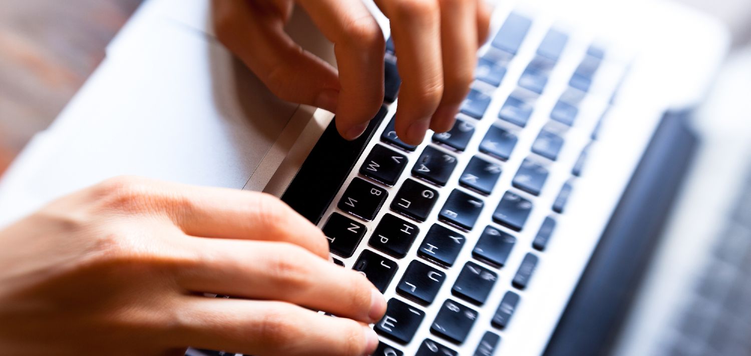 Mand skriver jobansøgning på en bærbar computer
